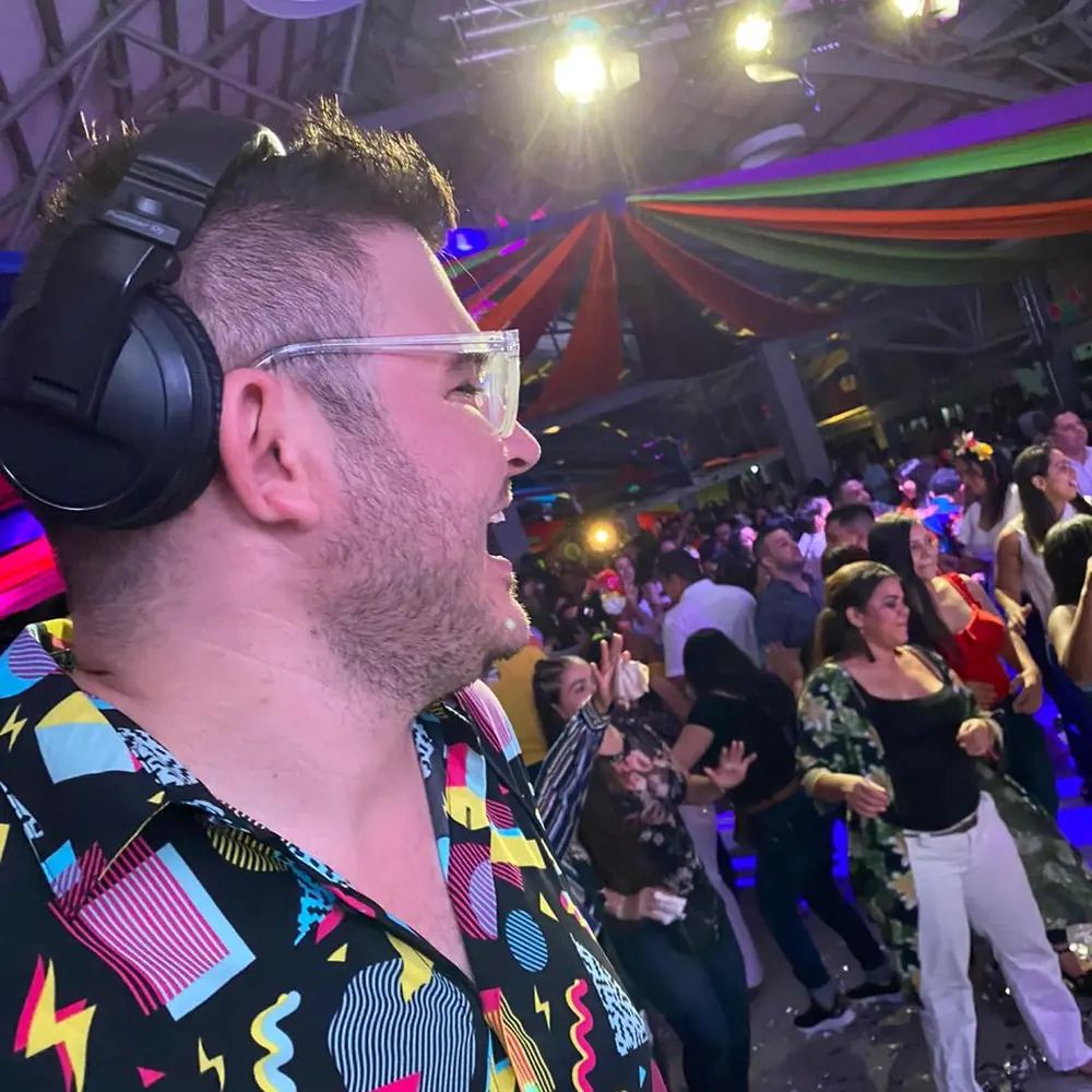 Simon Groove DJ en cabina con la pista llena de invitados bailando