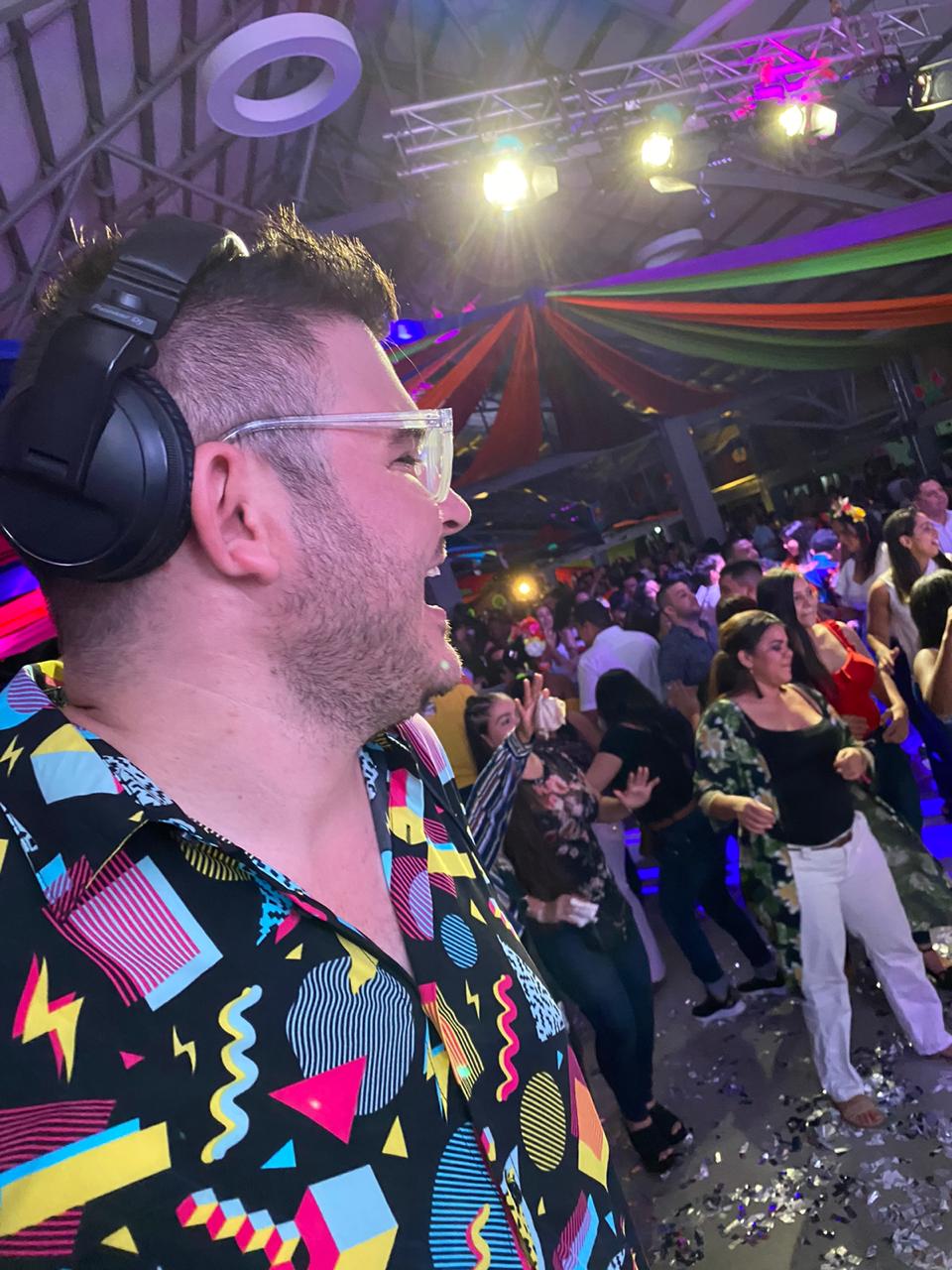 Simon Groove DJ in the booth with a packed floor and coloured lights at a party